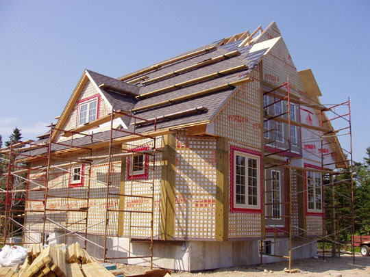 Windows, walls with siding completed on beachfront home. Roofing underway.