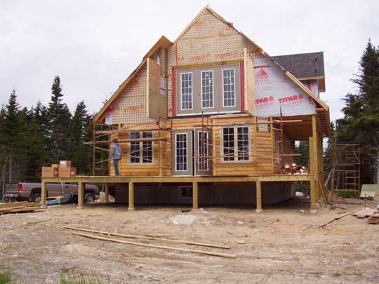 Wood siding partially installed, and roofing underway on new beachfront home.