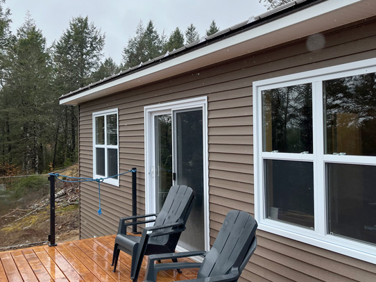 Compact cottage with deck, and glass railing to maximize view of lake front